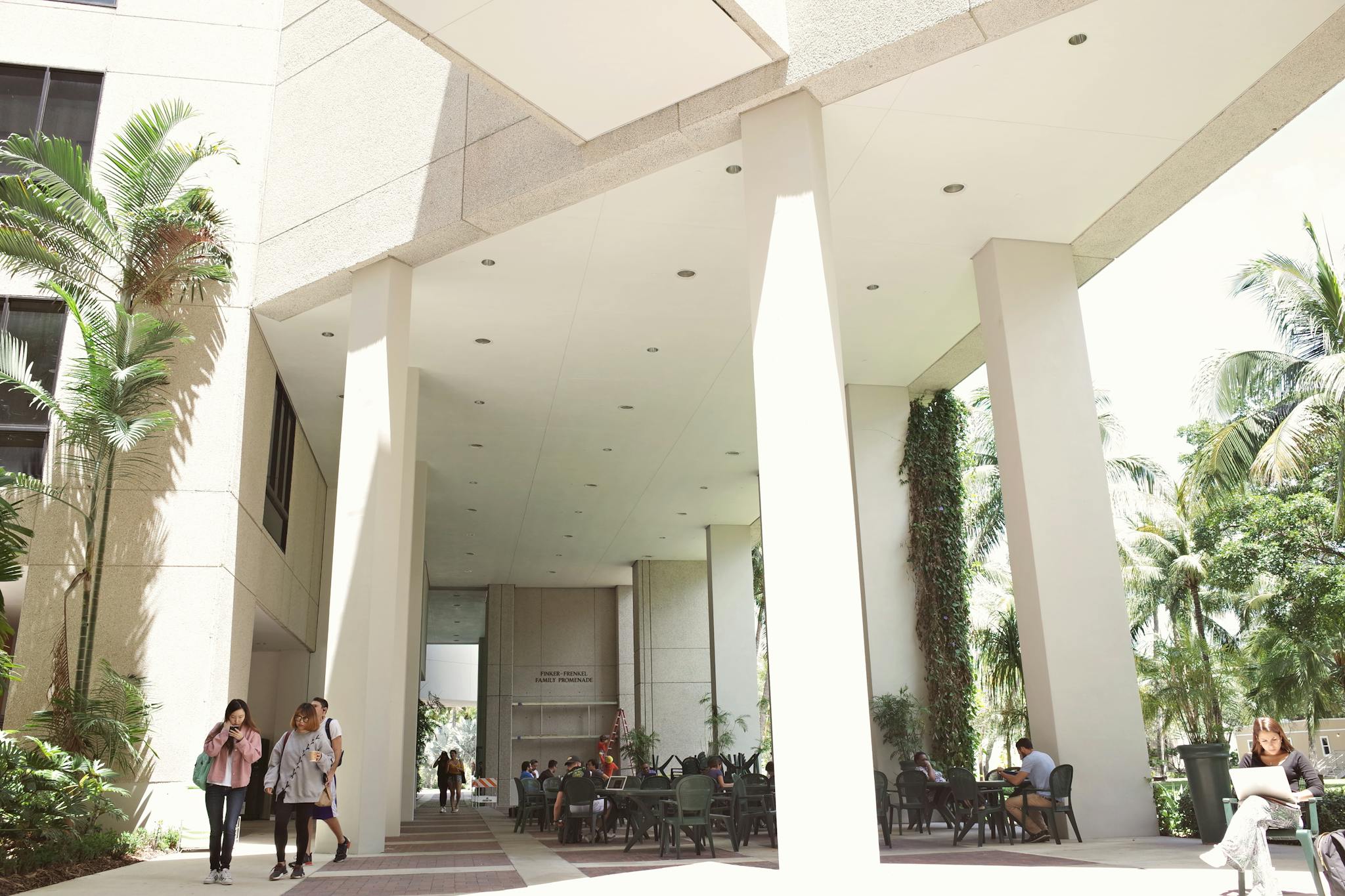 Students walking and studying on a sunny day at a Florida university campus.